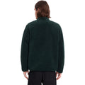 Vista trasera de hombre con sudadera Volcom Muzzer Fuzzar Zip en color verde escarabajo, mostrando el ajuste en la espalda y el corte amplio de la prenda.