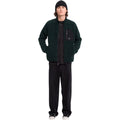 Hombre con gorro y sudadera Volcom Muzzer Fuzzar Zip en color verde escarabajo de cuerpo entero, vista frontal mostrando el corte amplio y la cremallera completa.
