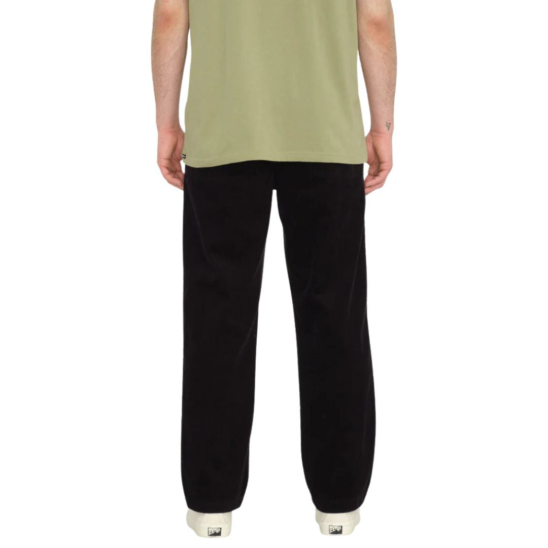 Modelo de espaldas vistiendo pantalón VOLCOM Psychstone EW color negro, plano medio.