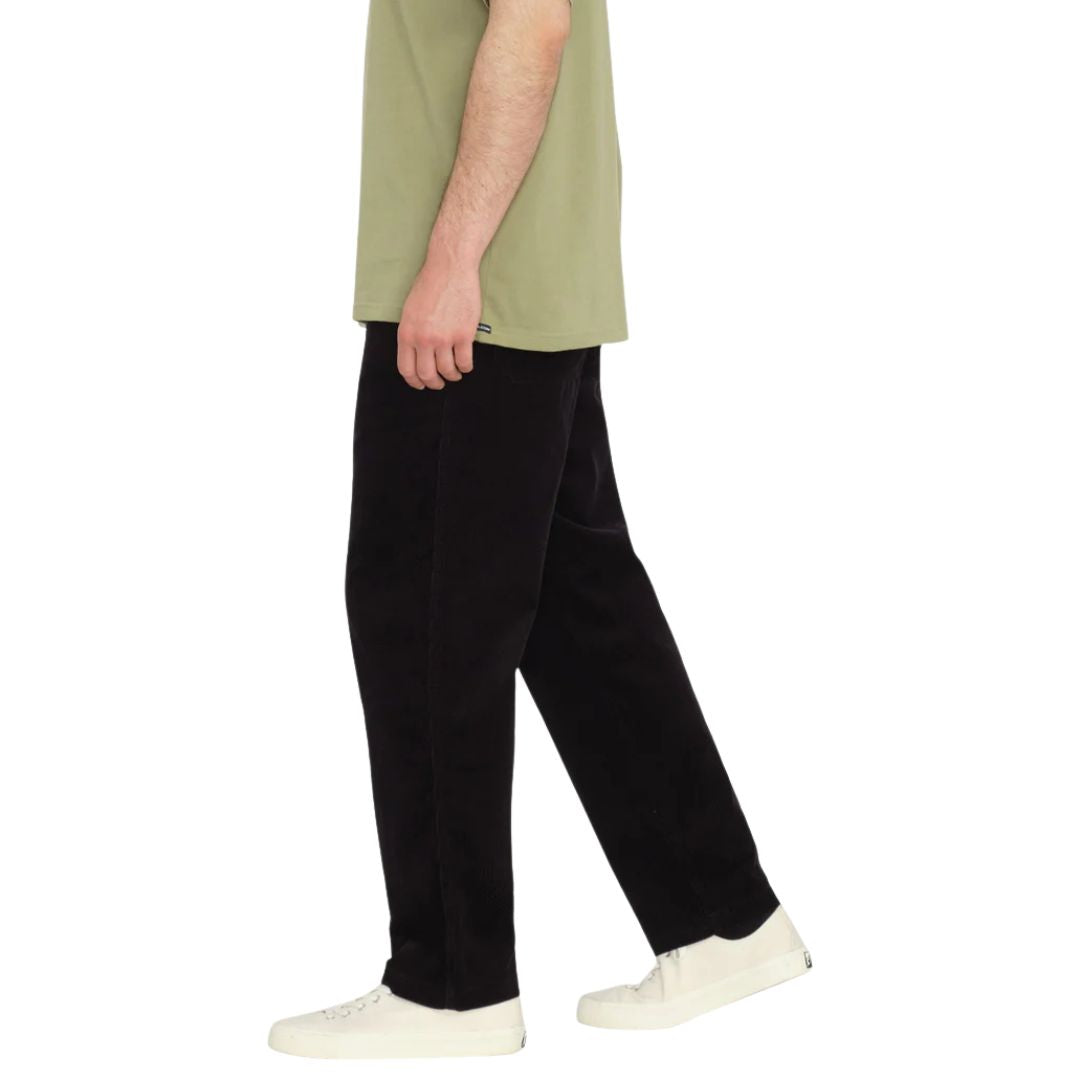 Modelo caminando con pantalón VOLCOM Psychstone EW color negro, vista lateral.