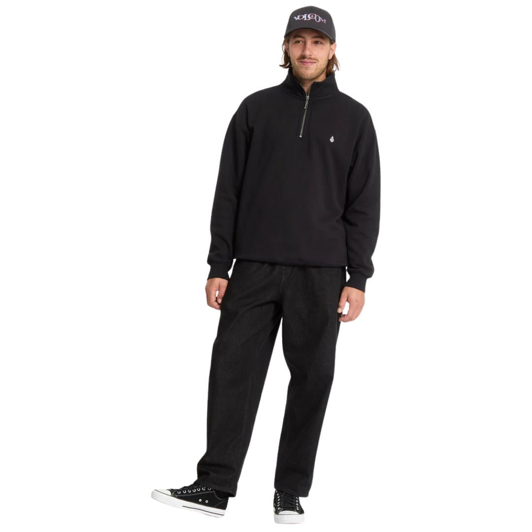 Sudadera Volcom Single Stone Quarter Zip negra para hombre, vista tres cuartos con pantalones anchos.