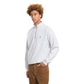 Modelo con el jersey Volcom Single Stone Quarter Zip en color gris hueso jaspeado, vista de perfil con la mano en el bolsillo y la mirada hacia atrás.