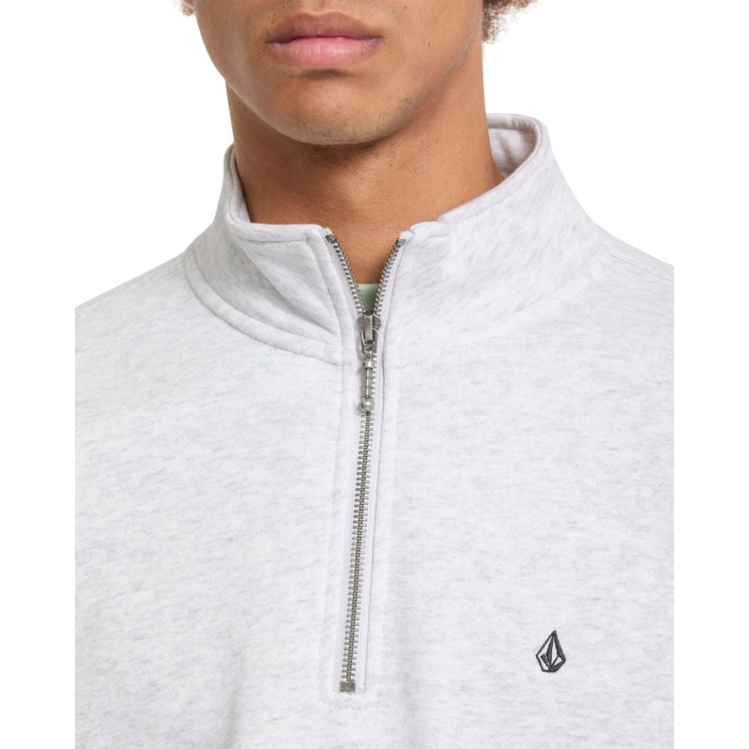 Detalle en primer plano del cuello alto y la cremallera media del jersey Volcom Single Stone Quarter Zip en color gris hueso jaspeado, con el mentón del modelo en encuadre.