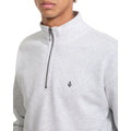 Detalle en primer plano de la cremallera media y el logo de la piedra Volcom bordado en el pecho del jersey Single Stone Quarter Zip en color gris hueso jaspeado.