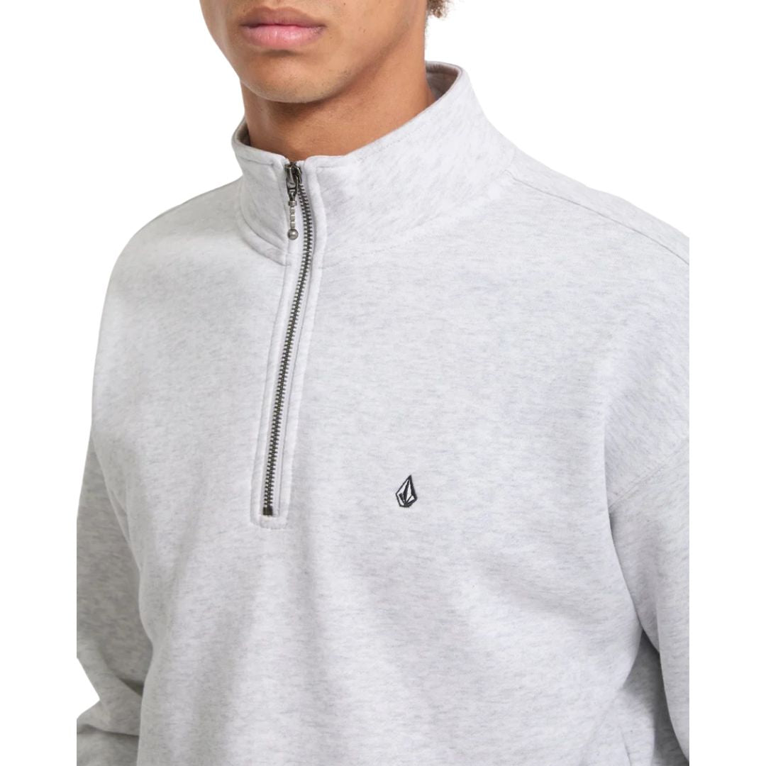 Detalle en primer plano de la cremallera media y el logo de la piedra Volcom bordado en el pecho del jersey Single Stone Quarter Zip en color gris hueso jaspeado.