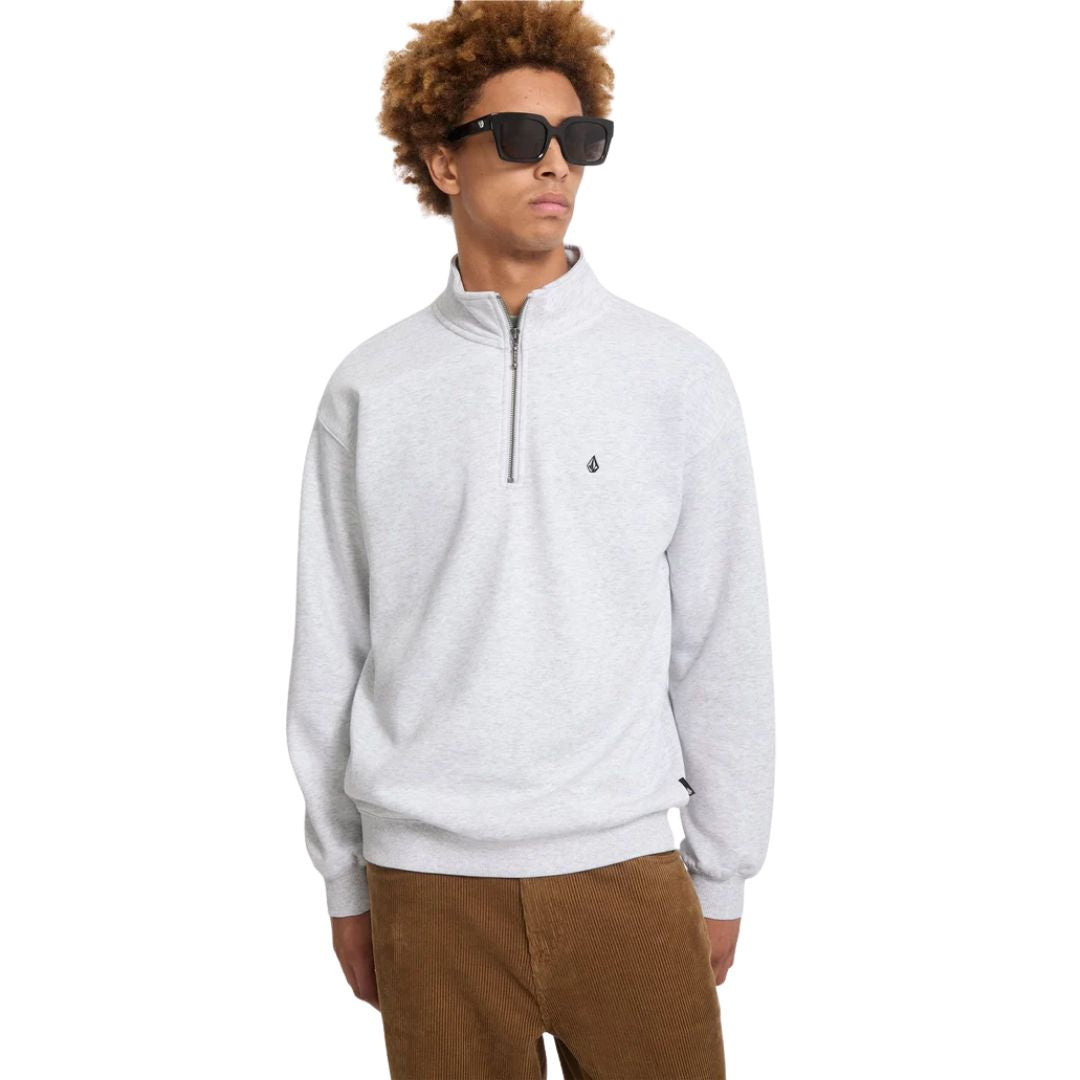 Modelo con el jersey Volcom Single Stone Quarter Zip en color gris hueso jaspeado, vista frontal con gafas de sol, mostrando el cuello alto y la cremallera media abierta.