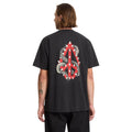 Vista trasera de modelo masculino con camiseta Volcom Snake Peace LSE SST negra mostrando estampado gráfico completo.