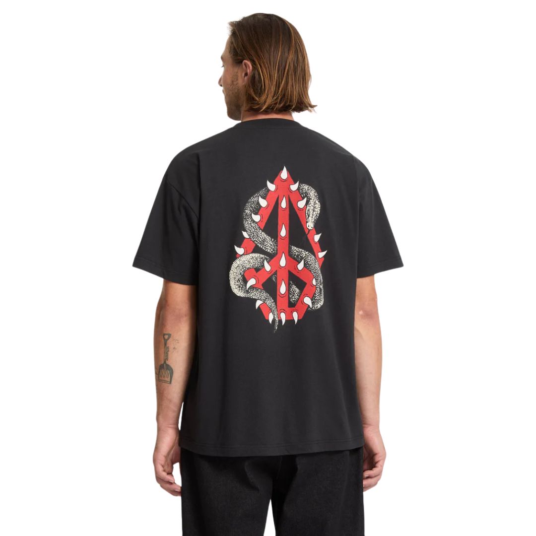 Vista trasera de modelo masculino con camiseta Volcom Snake Peace LSE SST negra mostrando estampado gráfico completo.