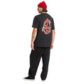 Modelo masculino de espaldas con camiseta Volcom Snake Peace LSE SST negra mostrando estampado trasero completo.