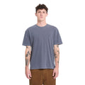 Modelo con la camiseta Volcom Solid Stone EMB SST en color storm blue, vista frontal con gafas de sol, manos en los bolsillos y logo bordado a la vista en el pecho.