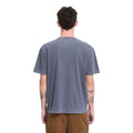 Camiseta Volcom Solid Stone EMB SST en color storm blue, vista frontal con gafas de sol y manos en los bolsillos, encuadre más cerrado sobre el torso y el cuello redondo.