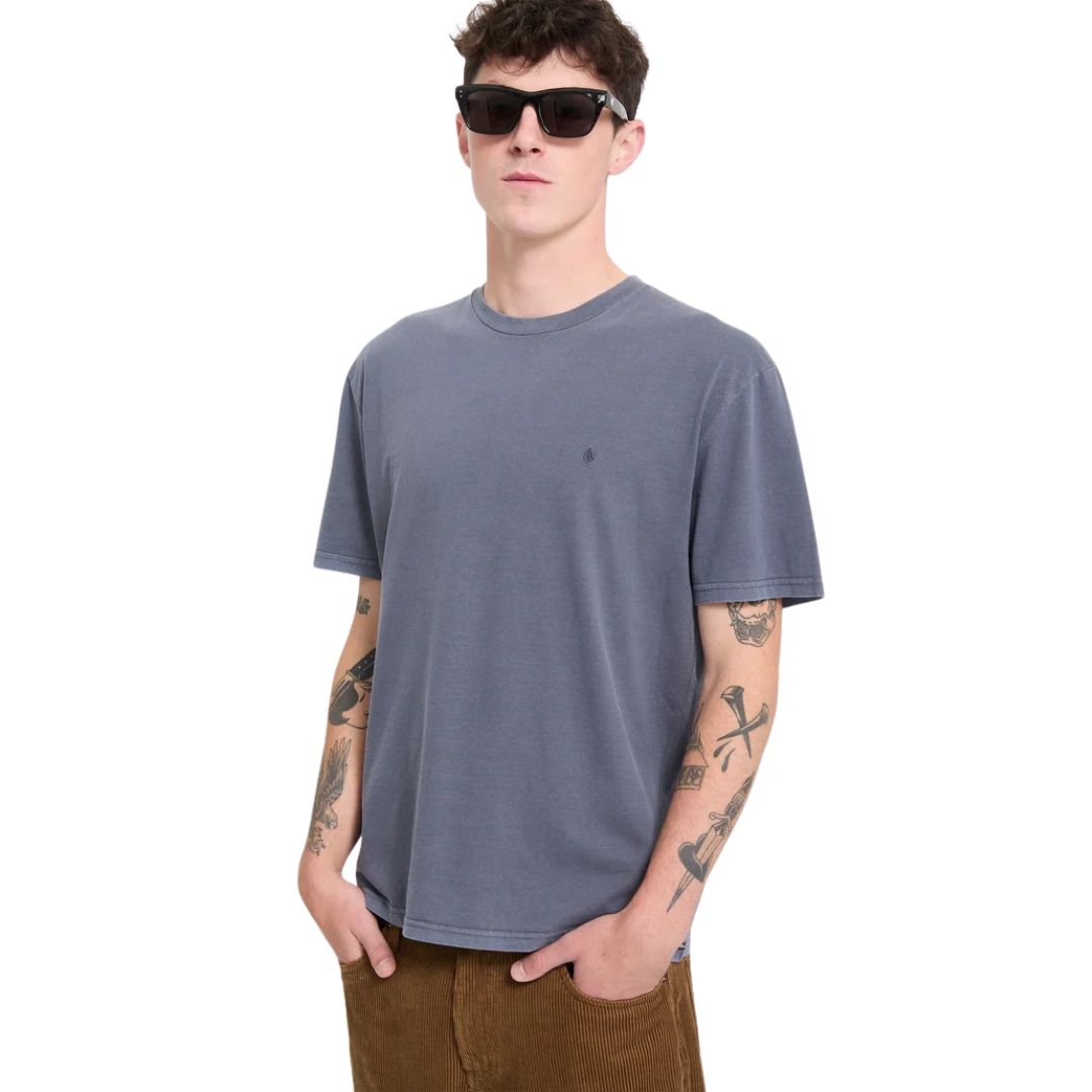 Modelo con la camiseta Volcom Solid Stone EMB SST en color storm blue, vista frontal sin gafas, con los brazos relajados a los lados mostrando el logo bordado en el pecho.