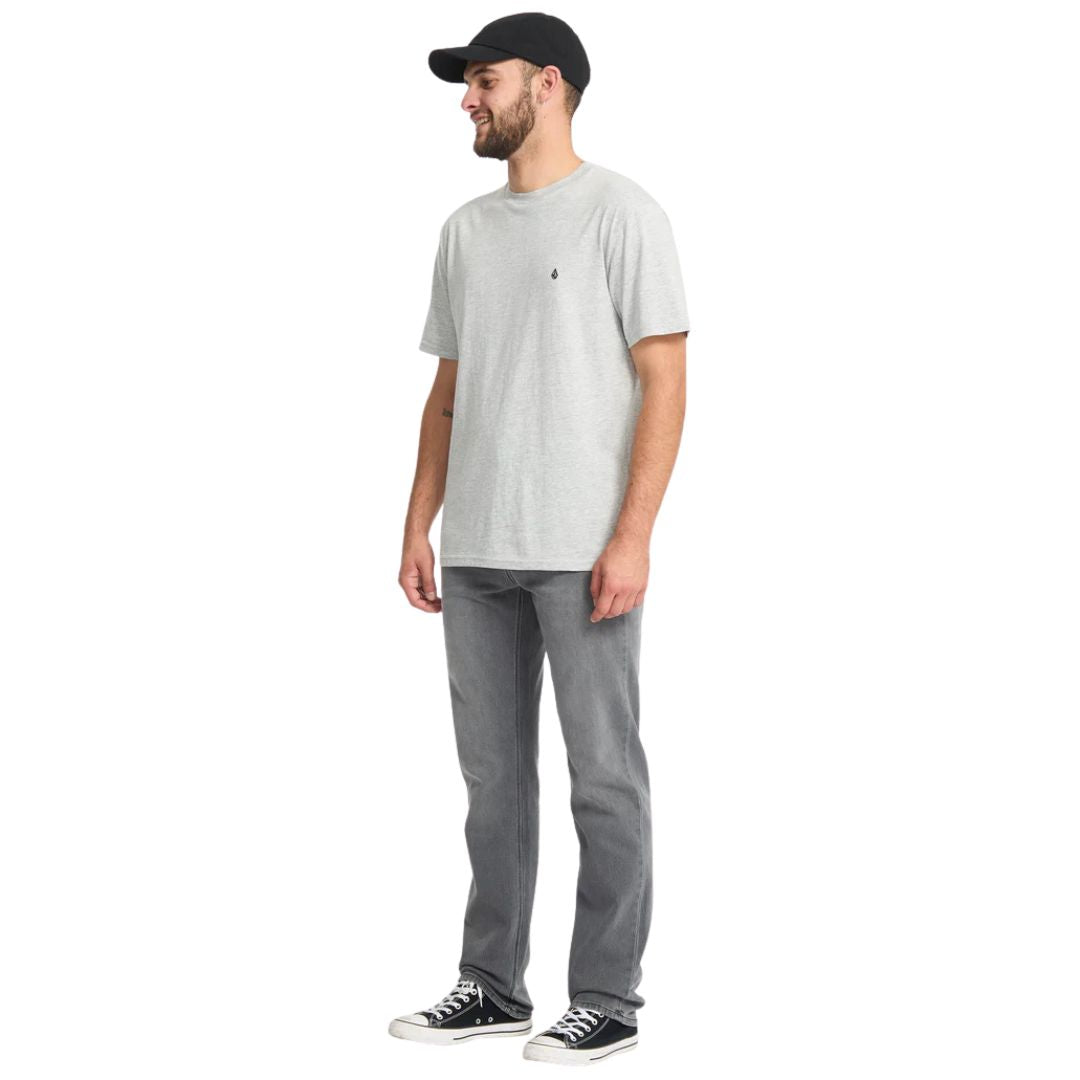 Vista tres cuartos de los vaqueros Volcom Solver Denim gris Concrete en modelo masculino con camiseta gris y gorra negra.