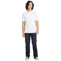 Modelo de pie vistiendo pantalón vaquero Volcom Solver Denim color New Washed Blue combinado con camiseta blanca y zapatillas negras.