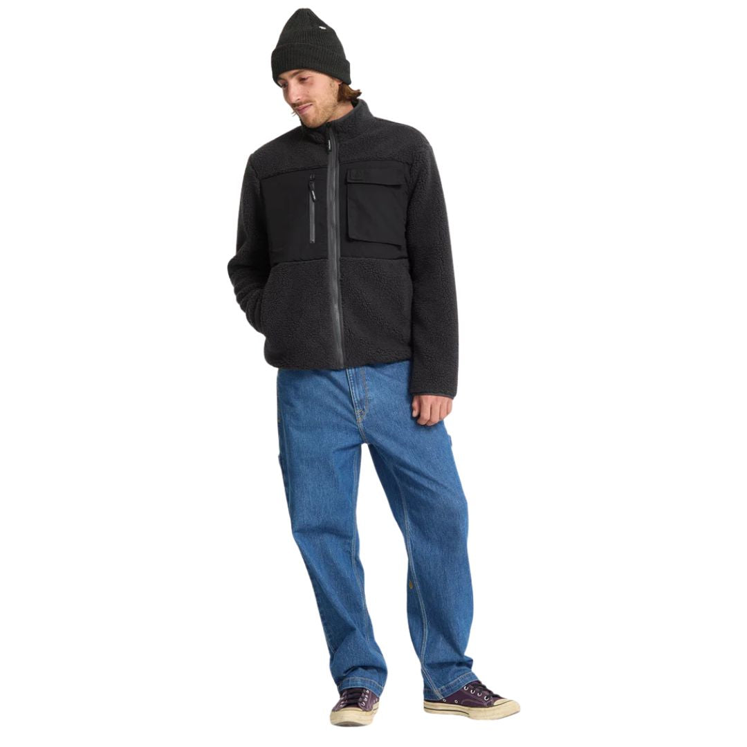 Modelo de pie con chaqueta Volcom Storm Stone Zip negro posando de lado.