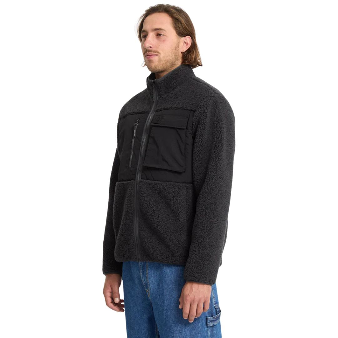 Modelo de pie con chaqueta Volcom Storm Stone Zip negro, vista lateral.