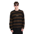 Hombre sonriente con gafas de sol y jersey Volcom Striperstand en color negro de rayas, vista frontal de medio cuerpo con el logo Volcom bordado en el pecho.