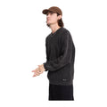 Modelo con gorra y el jersey de punto Volcom Thermowhy Sweater negro, vista lateral de la manga larga con puño de canalé y la etiqueta Volcom en el bajo