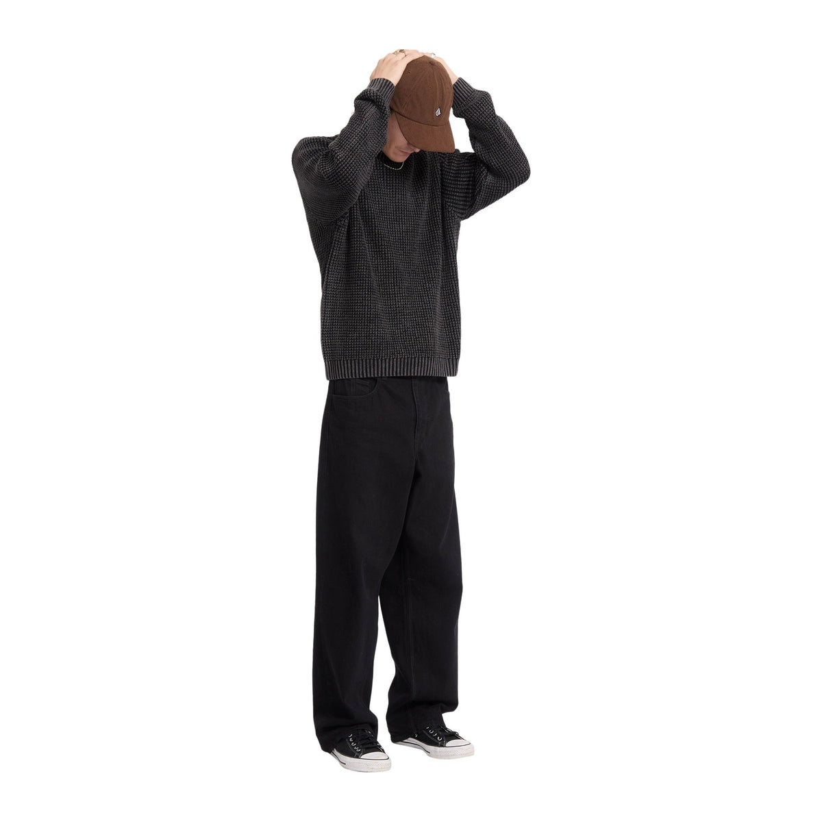 Modelo de cuerpo entero de espaldas con las manos en la cabeza y el jersey de punto gofrado Volcom Thermowhy Sweater negro, combinado con pantalón ancho
