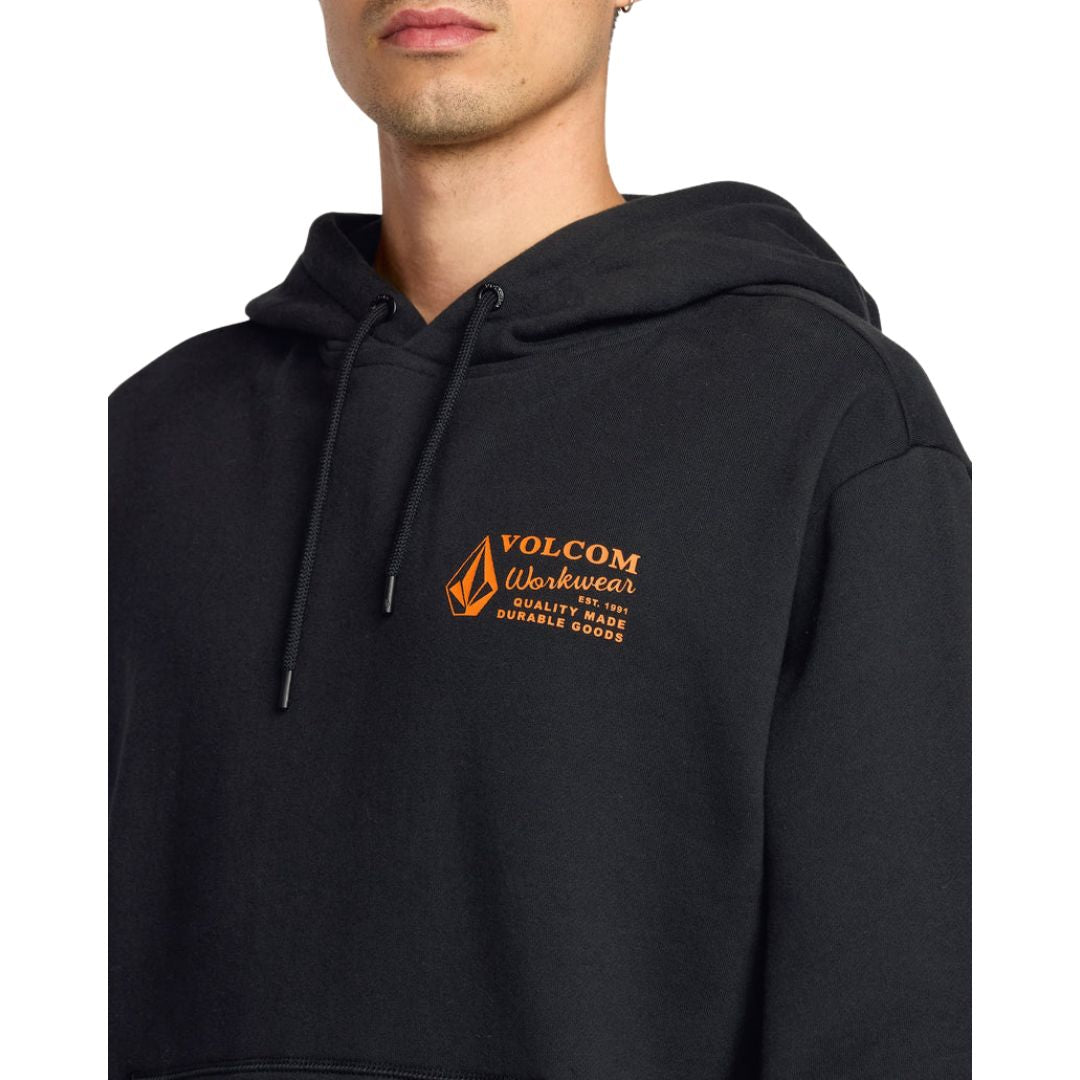 Modelo vistiendo sudadera Volcom Workwear PO negra con logotipo naranja en el pecho, vista frontal.