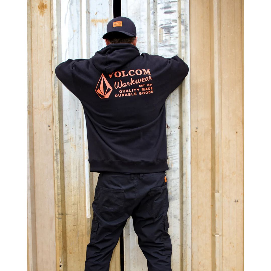 Modelo de espaldas usando sudadera Volcom Workwear PO negra, logotipo Volcom Workwear naranja en la parte trasera.