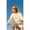 Mujer con gafas de sol Warmouth Candy Gradient Brown puestas en bicicleta, montura ochavada con lente marrón degradada, look casual veraniego.